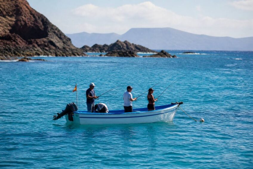 Een realistische foto van een visboot met hengels op de oceaan voor de rotsachtige kust van Lanzarote